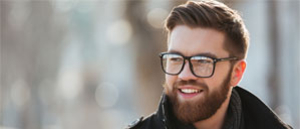 Symbolbild lächelnder junger Mann mit Brille und VOllbart
